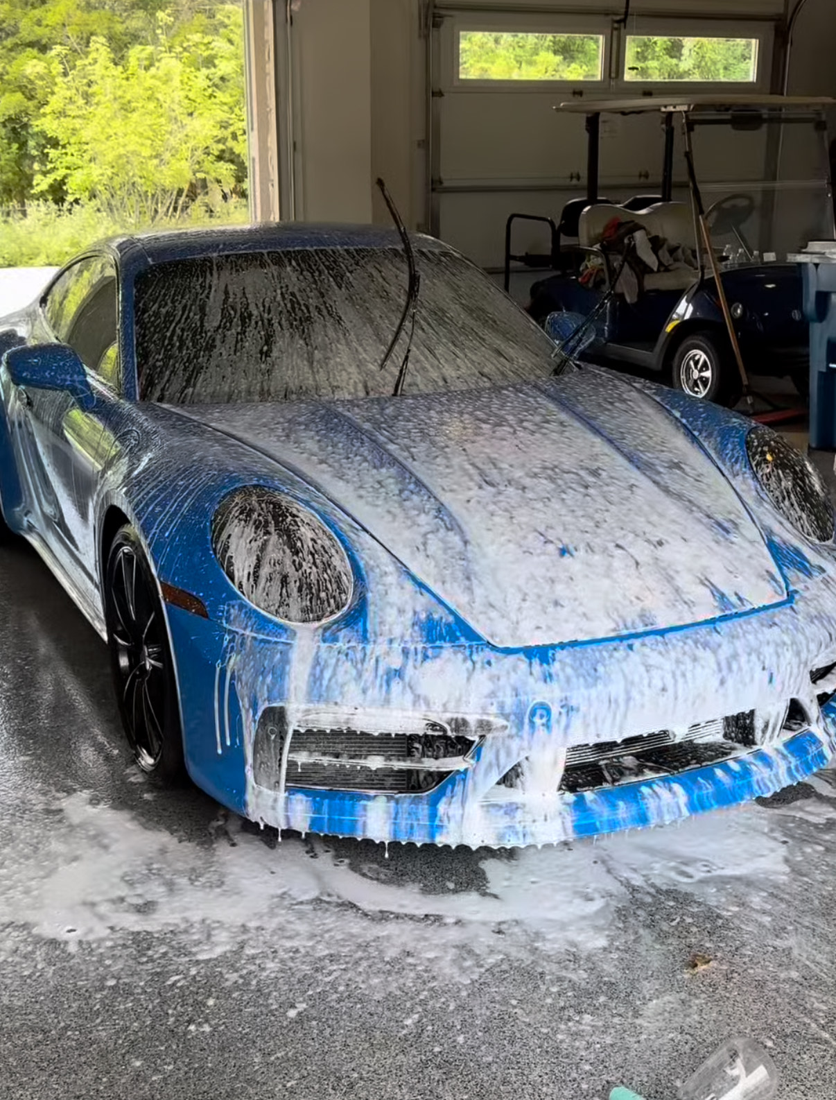 Professional car detailing - Blue Porsche covered in soap suds during washing process